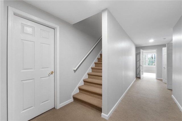 hall featuring light carpet, stairs, and baseboards