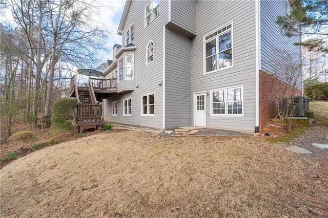 rear view of property featuring stairs, a deck, and brick siding