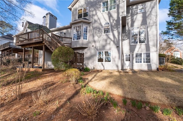 rear view of property with driveway, a chimney, and a wooden deck