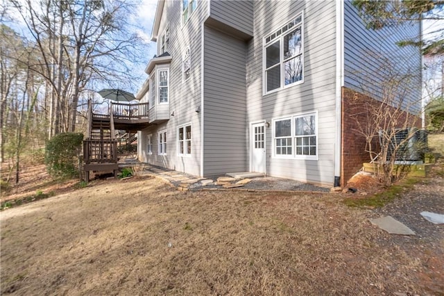 view of property exterior with brick siding, stairs, and a wooden deck