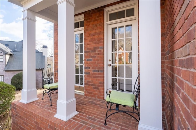 view of exterior entry featuring brick siding and a porch