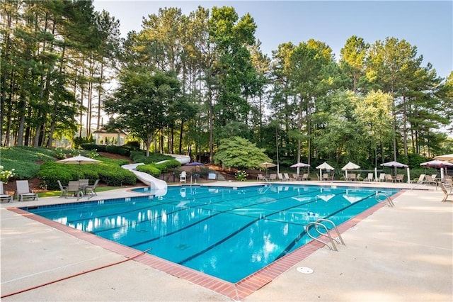 community pool with a water slide and a patio