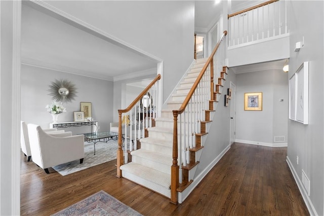 staircase featuring baseboards, visible vents, ornamental molding, and wood finished floors