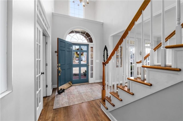 foyer with baseboards, a towering ceiling, stairway, wood finished floors, and a chandelier