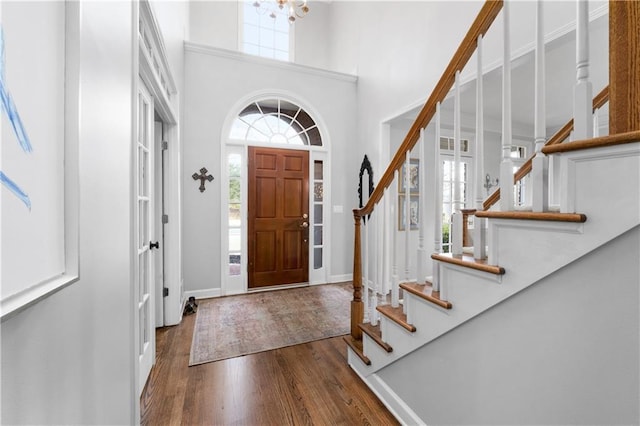 foyer featuring a chandelier, a high ceiling, wood finished floors, baseboards, and stairs