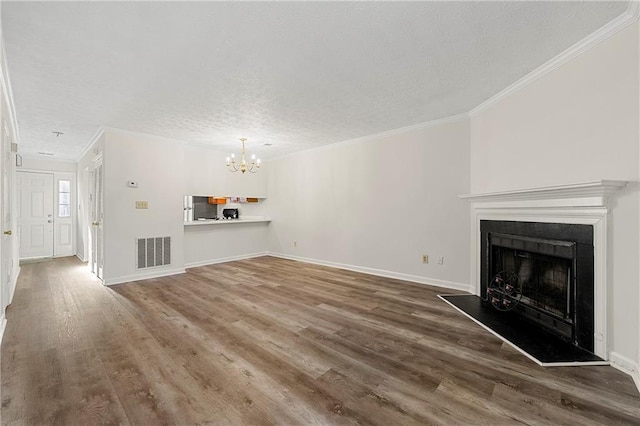 unfurnished living room featuring a fireplace with raised hearth, wood finished floors, visible vents, baseboards, and crown molding