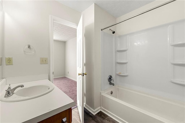 bathroom with shower / bathing tub combination, a textured ceiling, baseboards, and vanity