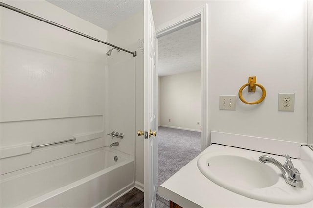 full bath featuring tub / shower combination, a textured ceiling, baseboards, and vanity