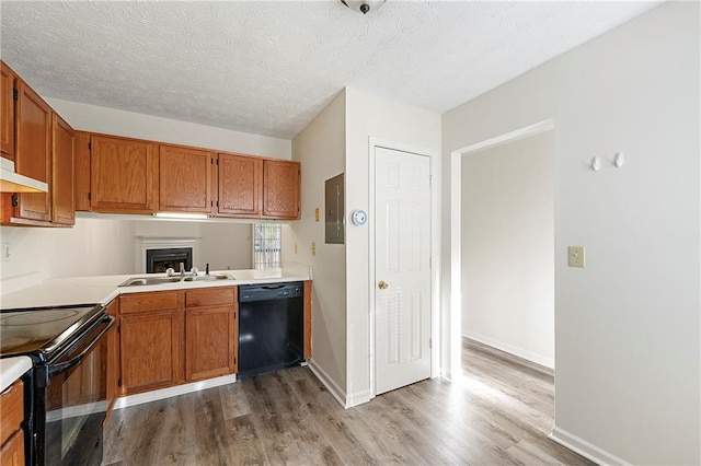 kitchen with black appliances, light countertops, a sink, and wood finished floors