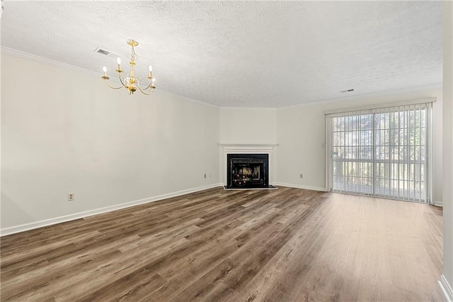 unfurnished living room with a textured ceiling, a chandelier, a fireplace with flush hearth, wood finished floors, and crown molding