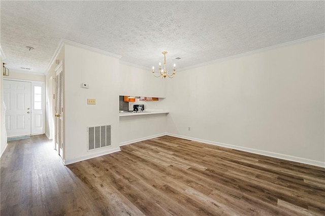 unfurnished dining area featuring a chandelier, a textured ceiling, wood finished floors, visible vents, and ornamental molding