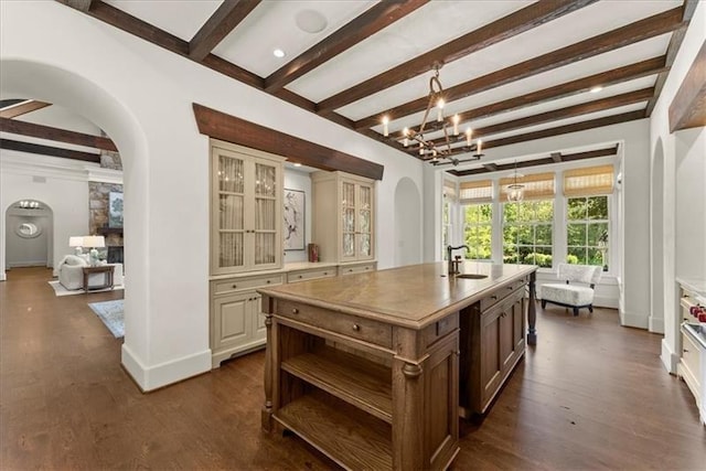 kitchen with a chandelier, beamed ceiling, a center island with sink, and cream cabinetry