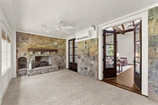 unfurnished living room featuring wood ceiling, french doors, a fireplace, a wall mounted AC, and ceiling fan