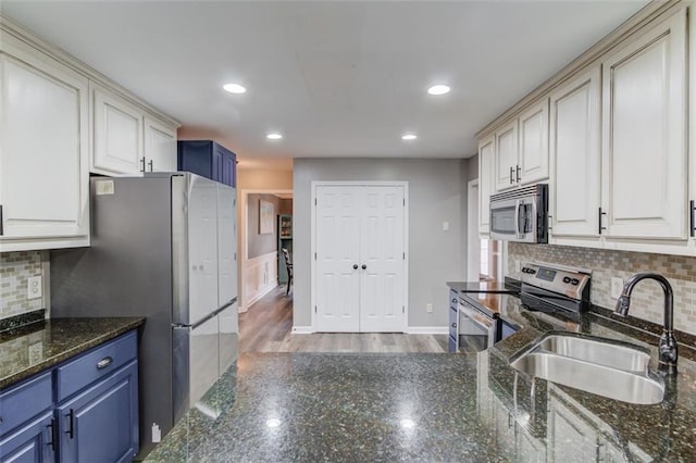 kitchen featuring sink, blue cabinetry, dark stone countertops, decorative backsplash, and stainless steel appliances