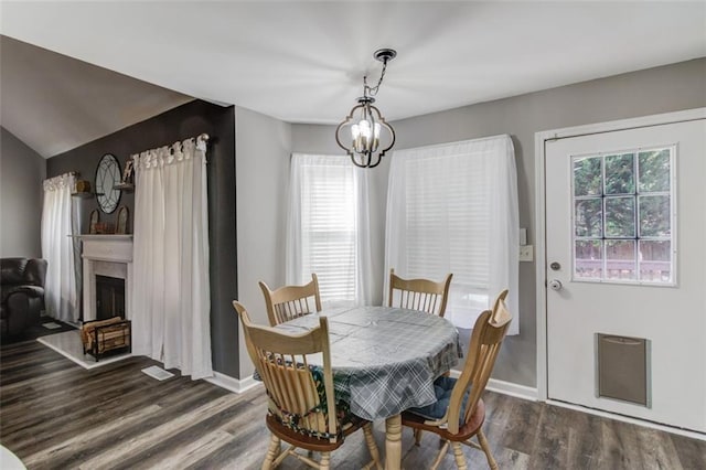 dining room with a notable chandelier, vaulted ceiling, and dark hardwood / wood-style floors