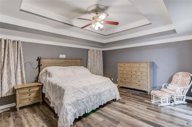 bedroom featuring ceiling fan, hardwood / wood-style floors, a tray ceiling, and ornamental molding