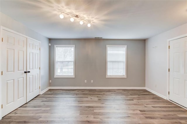 unfurnished bedroom with track lighting and light hardwood / wood-style flooring