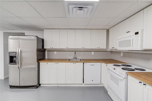 kitchen featuring white appliances, white cabinetry, butcher block counters, sink, and a drop ceiling