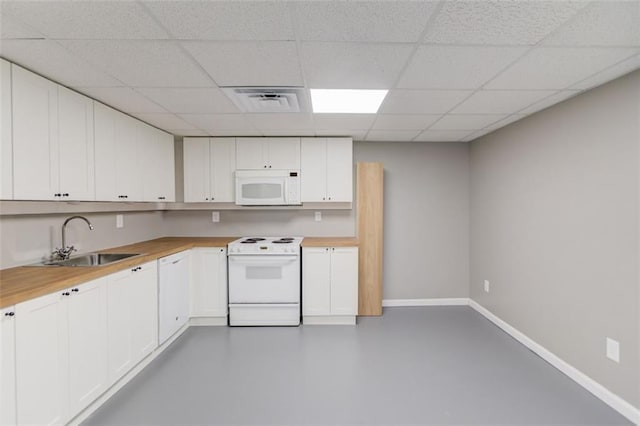 kitchen featuring white appliances, a paneled ceiling, wood counters, white cabinetry, and sink