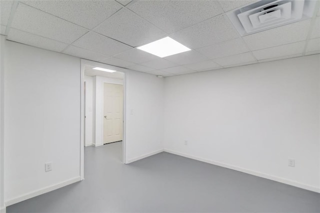 spare room with a paneled ceiling and concrete flooring