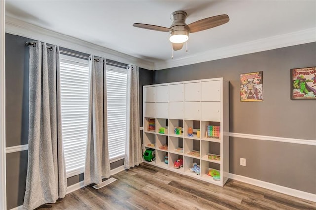 rec room with ceiling fan, ornamental molding, and wood-type flooring