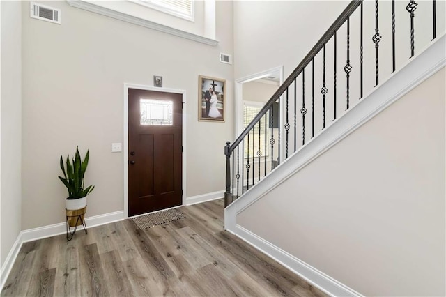 foyer entrance featuring stairs, visible vents, baseboards, and wood finished floors