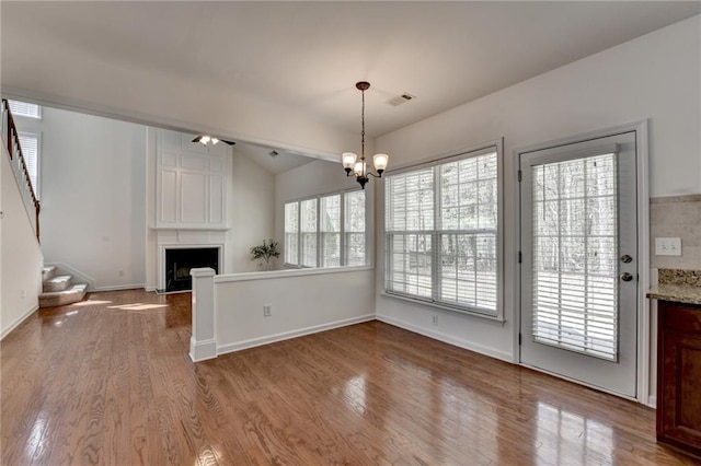 580 Hammersmith Dr, Suwanee, GA 30024 - unfurnished dining area featuring a large fireplace, wood finished floors, stairway, baseboards, and vaulted ceiling
