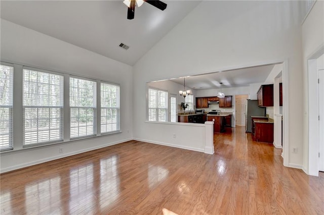 580 Hammersmith Dr, Suwanee, GA 30024 - unfurnished living room with a chandelier, a ceiling fan, high vaulted ceiling, light wood-style flooring, and baseboards