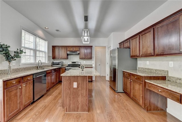 580 Hammersmith Dr, Suwanee, GA 30024 - kitchen with appliances with stainless steel finishes, under cabinet range hood, light wood finished floors, an island with sink, and light stone countertops