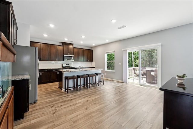 519 Magnolia Dr, Dawsonville, GA 30534 - kitchen featuring appliances with stainless steel finishes, a breakfast bar, light wood finished floors, decorative backsplash, and recessed lighting