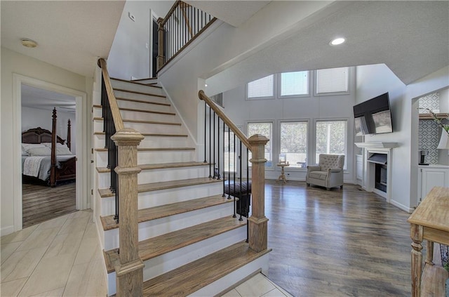 317 Shenandoah Dr NE, Calhoun, GA 30701 - staircase featuring a towering ceiling, a fireplace, wood finished floors, baseboards, and recessed lighting