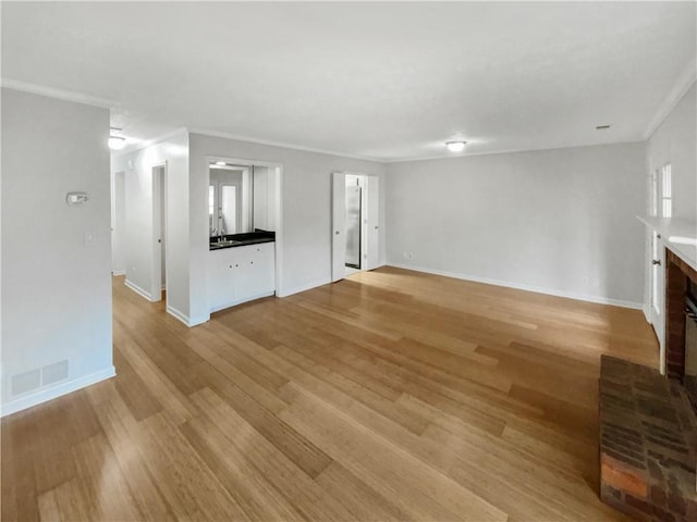 unfurnished living room with a fireplace, crown molding, light hardwood / wood-style flooring, and sink