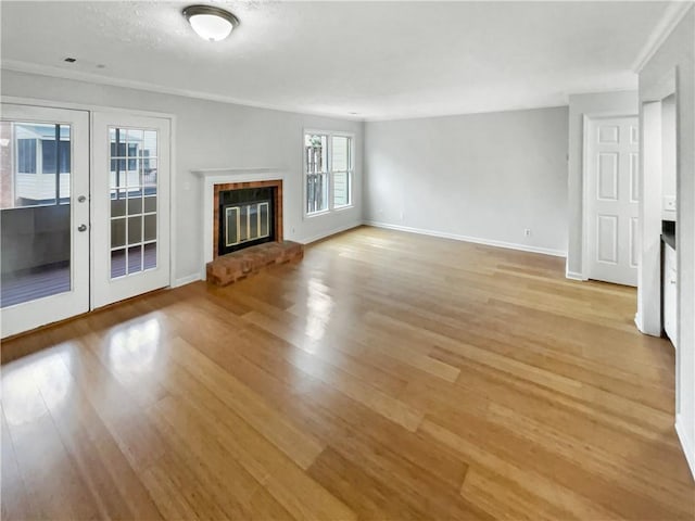 unfurnished living room featuring a fireplace, french doors, and light wood-type flooring