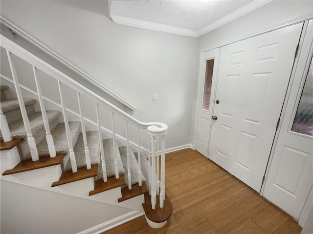 foyer entrance with hardwood / wood-style flooring, ornamental molding, and a textured ceiling