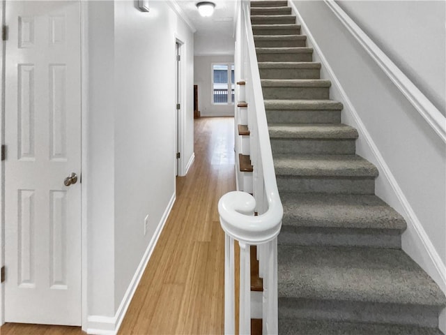 staircase with ornamental molding and hardwood / wood-style floors