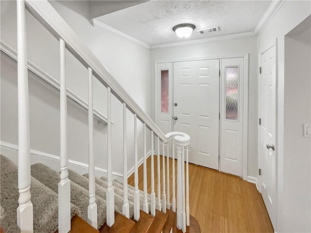 entrance foyer with hardwood / wood-style flooring, ornamental molding, and a textured ceiling