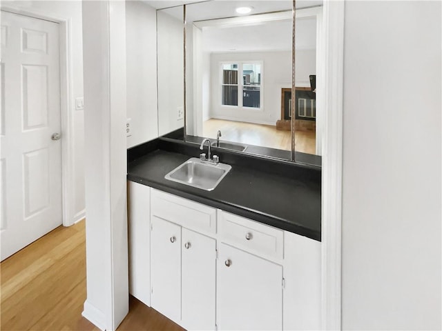 kitchen with wood-type flooring, sink, and white cabinets