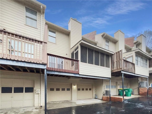 rear view of house featuring a garage and central AC