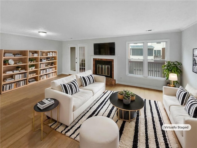 living room featuring light hardwood / wood-style flooring, a tile fireplace, and french doors