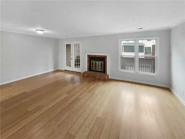 unfurnished living room with french doors, a fireplace, and light wood-type flooring