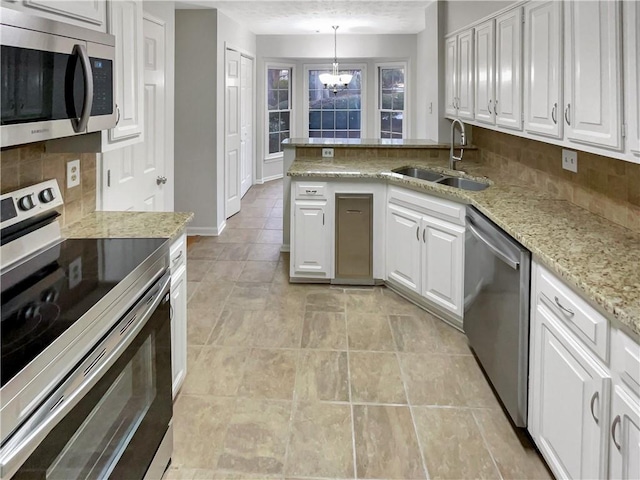 kitchen featuring stainless steel appliances, decorative light fixtures, and white cabinets