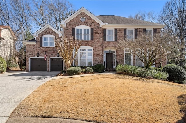 colonial house with brick siding, an attached garage, and concrete driveway