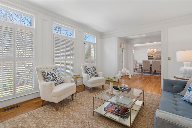 living room with wood finished floors, a healthy amount of sunlight, visible vents, and ornamental molding