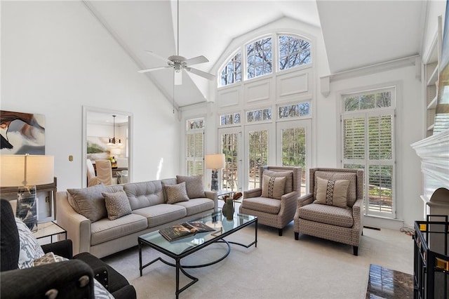 living area with a premium fireplace, light colored carpet, ceiling fan, and high vaulted ceiling