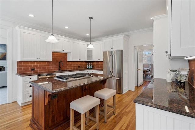 kitchen featuring a sink, stainless steel appliances, white cabinets, a kitchen bar, and crown molding