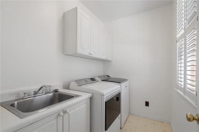 laundry area with baseboards, light floors, washer and dryer, cabinet space, and a sink