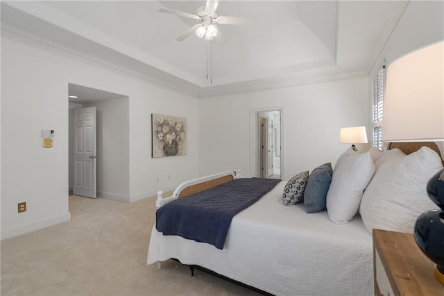 bedroom with ornamental molding, a ceiling fan, a tray ceiling, baseboards, and light colored carpet