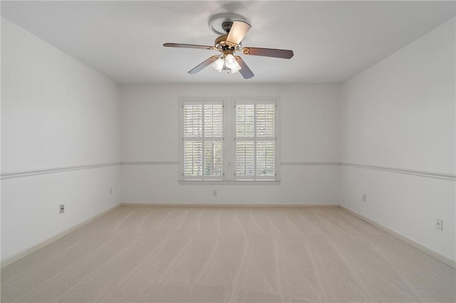 spare room featuring baseboards, light colored carpet, and a ceiling fan