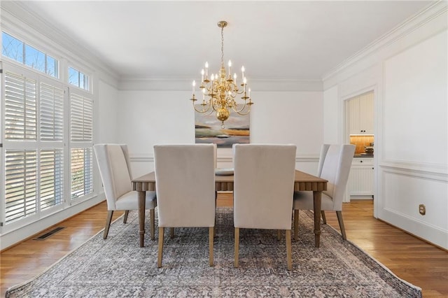 dining area with crown molding, wood finished floors, visible vents, and a chandelier