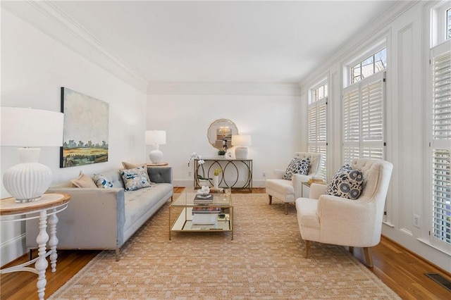 living room with visible vents, baseboards, wood finished floors, and crown molding